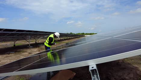 Black-African-male-engineer-testing-the-efficiency-of-a-photovoltaic-solar-panel-farm-installation-in-Africa,-professional-technician-wearing-helmet-doing-maintenance