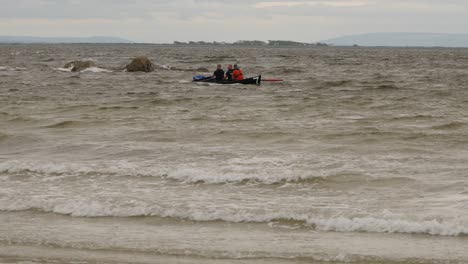 Eine-Gruppe-Von-Spitzensportlern-Rudert-Bei-Rauer-See-Mit-Dem-Currach-Boot-In-Richtung-Küste,-Nachdem-Sie-Am-70.-Jahrestag-Der-Currach-Rennen-In-Irland-Teilgenommen-Haben