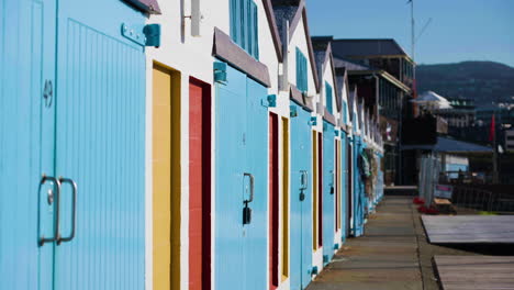 Slow-motion-establishing-shot-of-colourful-beach-huts-in-WQellington,-New-Zealand