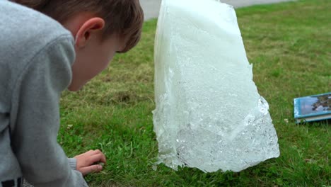A-curious-boy-is-checking-the-details-of-a-glacier-ice-block-outside-the-Glacier-Museum-in-Fjaerland-Norway---Slow-motion