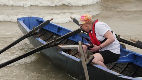 Una-Mujer-Solitaria-Saca-Agua-Del-Tradicional-Currach-De-Carreras-Irlandés-De-Madera-Antes-De-Competir.