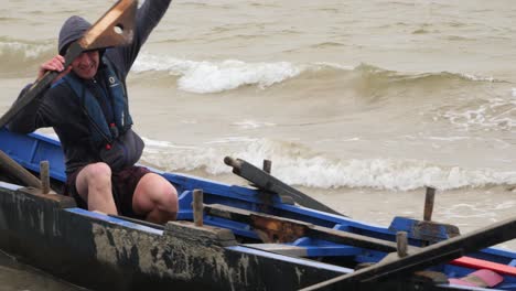 Man-sits-in-traditional-currach-boat-and-prepares-oars-to-race