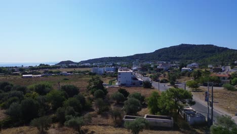 über-Der-Straße-Und-Grüner-Wald-In-Rhodos-Mit-Meer-Im-Hintergrund-In-Griechenland-Während-Des-Sommers,-Gefilmt-Mit-Der-Drohne-In-4k