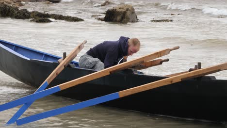 Ein-Einzelner-Mann-Rettet-In-Der-Sanften-Brandung-Ein-Traditionelles-Irisches-Boot-Aus-Currach