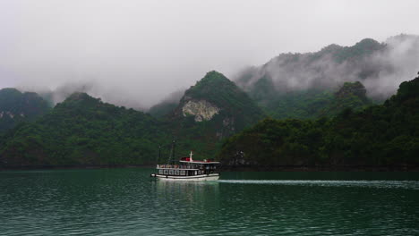Toma-Manual-De-Un-Barco-Turístico-Navegando-En-La-Ladera-De-Una-Montaña-De-Nueva-Zelanda-Con-Niebla.
