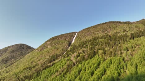 Kyrelvi-Wasserfall,-Der-Vom-Berggipfel-In-Vikoyri-In-Sogn-Norwegen-Herabstürzt-–-Luftaufnahme-Im-Abendsonnenlicht-Mit-Blick-Auf-Den-Berg-Mit-Fluss