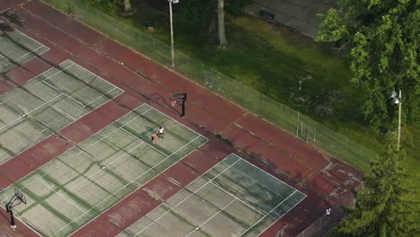 Bird's-eye-aerial-of-two-people-playing-on-adjacent-public-basketball-courts