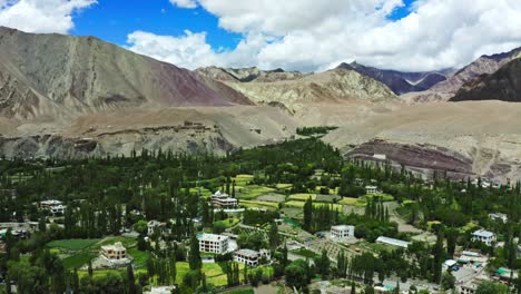 Cámara-Aérea-Moviéndose-Hacia-La-Ciudad-De-Leh,-Leh-Ladakh,-Hermosa-Vista-Del-Paisaje-En-La-Carretera-Alrededor-Con-Fondo-De-Montaña-Y-Cielo,-Leh,-Ladakh,-Jammu-Y-Cachemira,-India