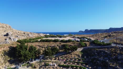 Agios-Pavlos-beach-in-Rhodes,-Greece-with-Acropolis-of-Lindos,-houses-and-Mediterranean-sea-during-the-day-filmed-with-the-drone