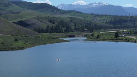 Canoe-on-lake-and-beautiful-mountain-backdrop---aerial