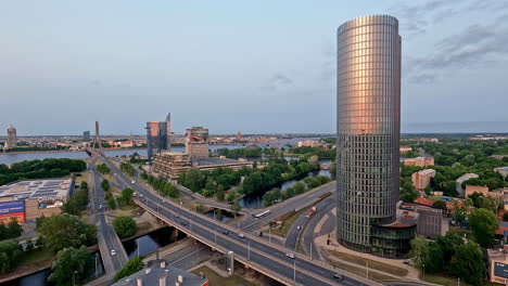 Time-lapse-of-cars-driving-through-intersection-crossing-river-boats,-sunlight-reflects-on-tower,-riga-latvia