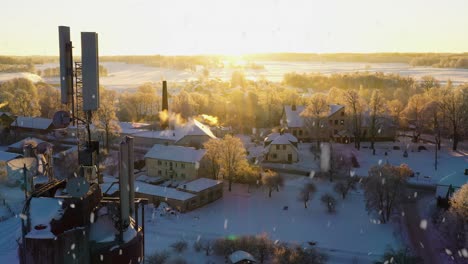 Powerful-cell-tower-antenna-in-small-rural-town-during-snowfall,-aerial-view