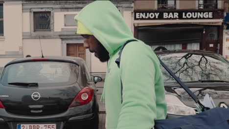 cinematic-epic-side-tracking-Dolly-shot-of-a-black-man-in-sport-wear-an-with-a-training-bag-pushing-in-from-wide-to-closeup-with-cars-parallaxing-effect