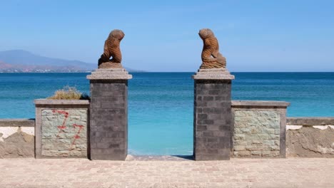 Scenic-view-of-popular-Cristo-Rei-beach,-turquoise-ocean-and-stone-fish-statues-in-capital-city-Dili,-Timor-Leste,-Southeast-Asia