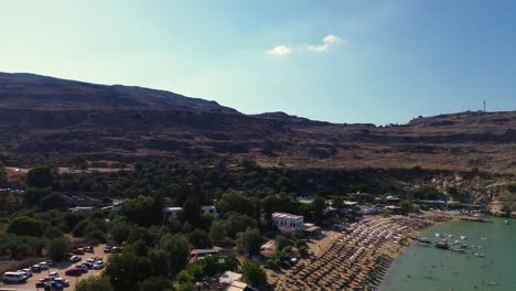 Strand-Und-Dorf-Von-Lindos-Auf-Rhodos,-Griechenland-Mit-Der-Akropolis-Von-Lindos,-Häusern-Und-Dem-Mittelmeer-Während-Des-Tages,-Gefilmt-Mit-Der-Drohne