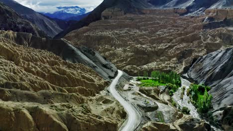 Luftdrohnenkamera,-Die-Von-Der-Leh-Hills-Road-Aus-Vorbeifliegt,-Einem-Sehr-Hohen-Ort-Und-Sehr-Schwer-Zu-Befahren,-Hinter-Bergen-Sichtbarer,-Von-Wolken-Getrübter-Himalaya