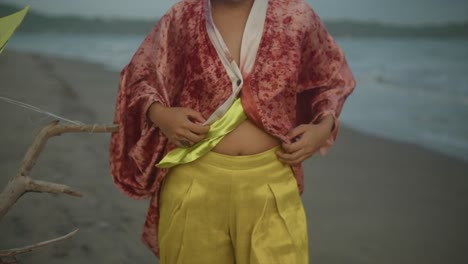 Eine-Sexy-Frau,-Die-Am-Windigen-Strand-Ihre-Bluse-Zuknöpft