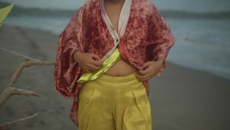 A-sexy-woman-buttoning-her-blouse-while-at-the-windy-seaside