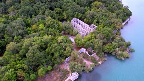 Aerial-of-Butrint-National-Park,-an-ancient-Roman-archaeological-site-with-an-old-church