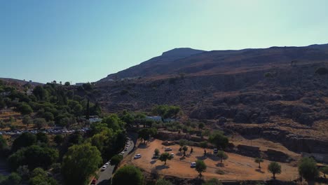 Lindos-forest-in-Rhodes,-Greece-with-Acropolis-of-Lindos,-houses-and-Mediterranean-sea-during-the-day-filmed-with-the-drone