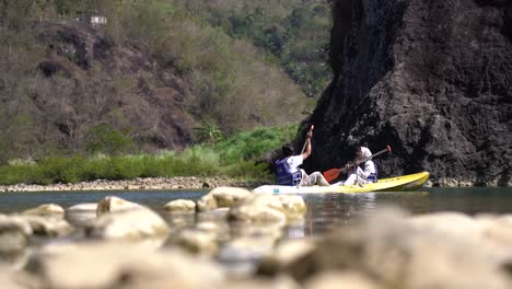 a-couple-enjoying-canoeing-on-the-river-with-cliffs-in-the-background