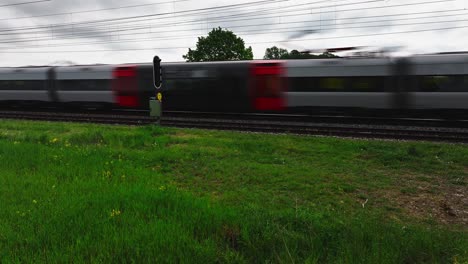 Train-tram-commuting-car-drives-by-on-rail-road-in-front-of-yellow-flower-field