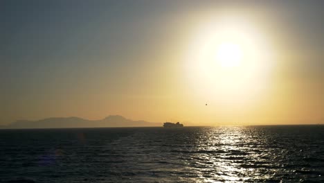 Blick-Auf-Den-Horizont-Und-Eine-Segelfähre-Auf-Den-Griechischen-Gewässern-Des-Ionischen-Meeres,-Alles-In-Den-Strahlen-Der-Untergehenden-Sonne