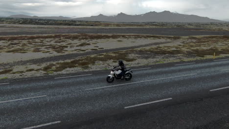 Solitary-motorcyclist-on-empty,-rural-road-in-Iceland,-dolly-sideways