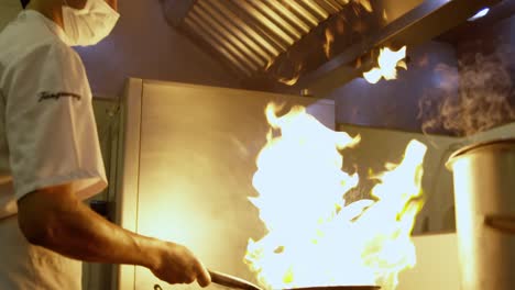 Un-Chef-Cocina-Comida-En-Una-Olla-Con-Fuego-Ardiendo-Encima