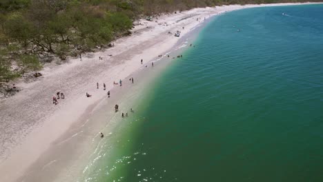 People-On-Sandy-Beach-Shore-Of-Popular-Conchal-Beach-Costa-Rica,-4K-Drone-Flyover
