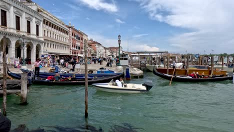 A-busy-congested-waterway-with-passing-boats-and-traditional-black-gondola-boats-in-Venice-on-a-beautiful-day,-Italy