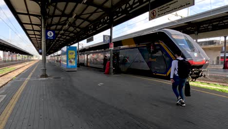 A-group-of-late-passengers-running-to-a-high-speed-electric-train-on-a-platform-at-Bologna-Central-Railway-station,-Italy