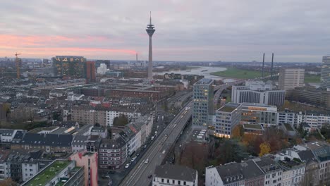 Aerial-drone-view-over-downtown-Dusseldorf-towards-Media-harbour-and-Rhine-tower-at-Dusk-with-colorful-sky