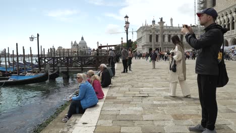 Slow-motion---Tourists-on-promenade-facing-lagoon-in-venice,-Italy-on-sunny-day