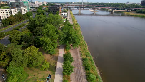 Aerial-tilt-up-shot-of-sport-park-at-shore-of-vistula-river-in-Warsaw-and-bridge-in-background