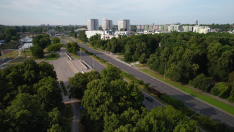 Luftaufnahme-Von-Autos-Auf-Der-Hauptstraße-In-Einem-Vorort-Der-Stadt-Warschau-An-Sonnigen-Tagen---Grüne-Waldbäume-Und-Ein-Fluss-In-Polen