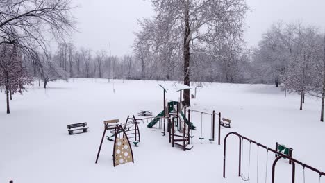Empty-kids-playground-covered-in-deep-snow-on-cold-winter-day,-aerial-view