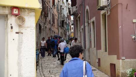 People-walk-through-narrow-cobbled-street-in-the-city-of-Rovinj,-Croatia