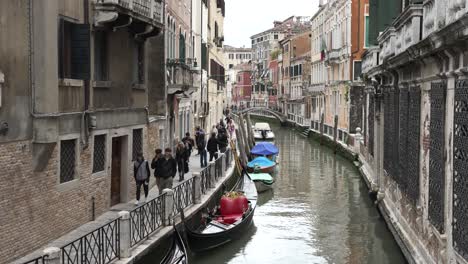 Slow-motion---People-walking-on-pavement-near-narrow-venetian-canal