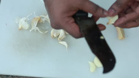 Chopping-garlic-on-a-White-Chopping-board-,Dismantling-with-a-knife-,-traditional-outdoor-cooking
