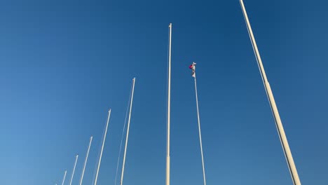 Indonesische-Flagge-Mit-Blauem-Himmel,-Der-Auf-Einer-Hohen-Stange-Zwischen-Leeren-Stangen-Flattert