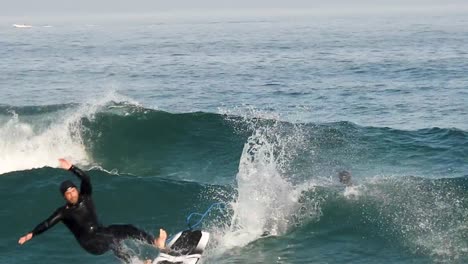 Surfer-falls-on-hydrofoil-surfboard-riding-blue-ocean-wave