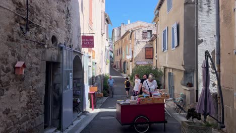 On-a-book-stall-in-the-old-streets-of-a-small-town-in-Southern-France,-people-are-browsing-and-selecting-books