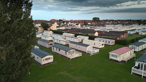 Drone's-view-of-Skegness-seaside-town-during-summer-sunset,-revealing-holiday-park,-beach,-sea,-and-caravans-in-sweeping-views
