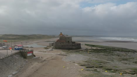 Drone-flying-towards-the-historical-fort-in-Ambleteuse-France-during-low-tide