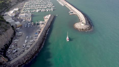 Revealing-4K-drone-view-of-the-nautical-port-of-Oropesa-del-Mar-following-a-small-sailing-boat,-Spain