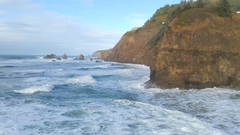 Aufschlussreiche-Szene-Mit-Meereswellen,-Die-In-Einen-Wunderschönen-Strand-An-Der-Küste-Von-Oregon-Mit-Klippen-Im-Hintergrund-Rollen