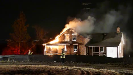 Wide-Shot-In-The-Night-Of-House-On-Fire-With-Fire-Fighter-Walking-Past-In-Brampton