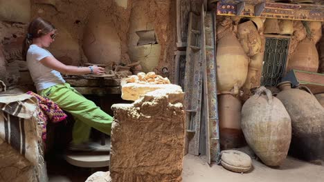 Young-potter-female-apprentice-at-work-with-clay-in-rural-workshop