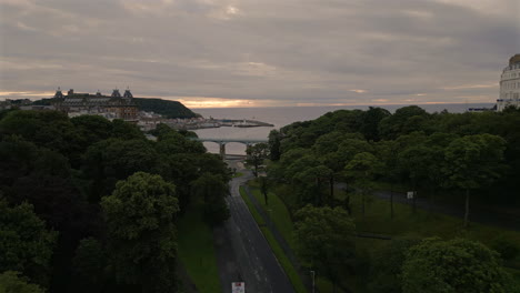 Establishing-Drone-Shot-down-Valley-Road-in-Scarborough-to-Beachfront-at-Overcast-Sunrise